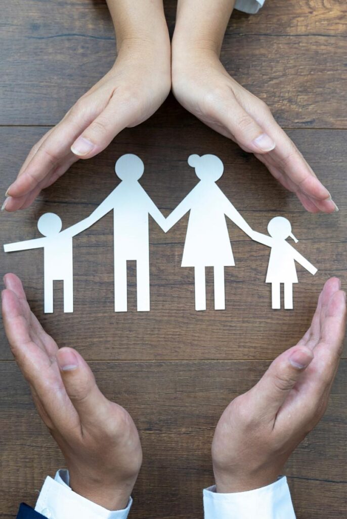 Hands held over a paper cutout of a family